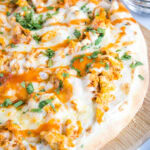 Close up of the edge of a buffalo chicken pizza topped with parsley