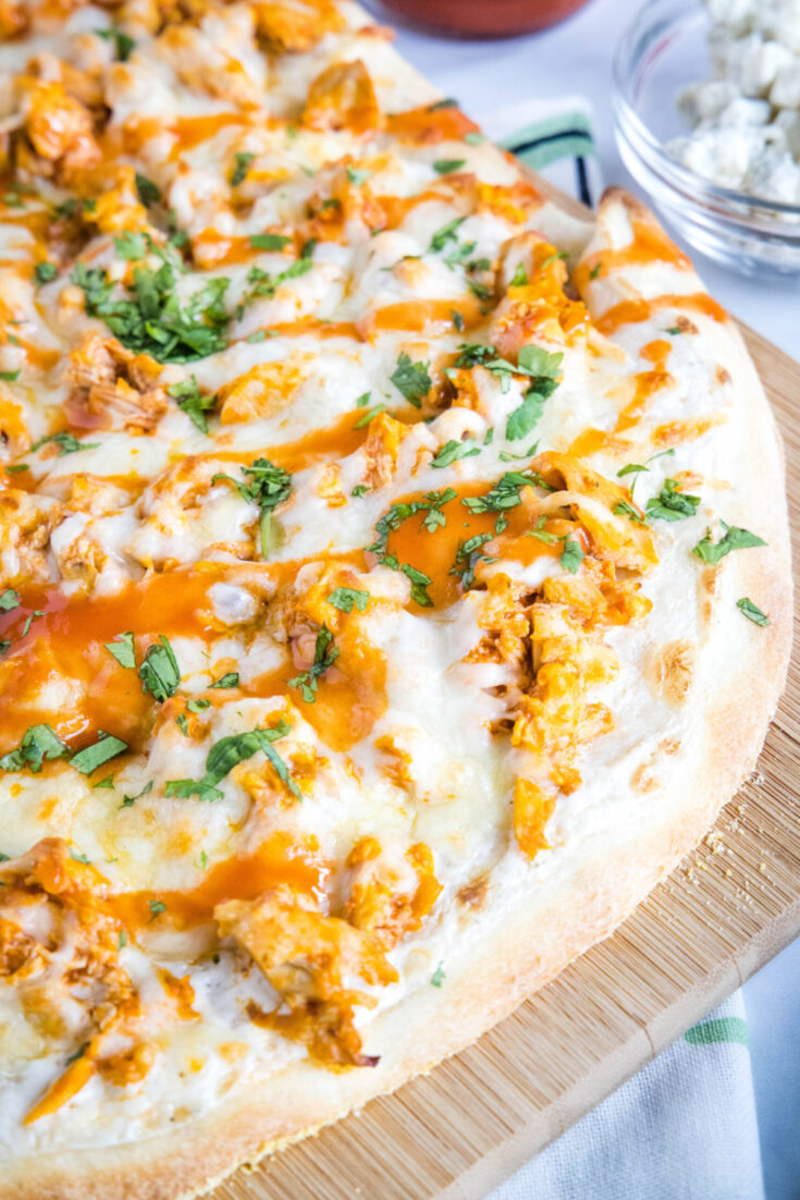 Close up of the edge of a buffalo chicken pizza topped with parsley