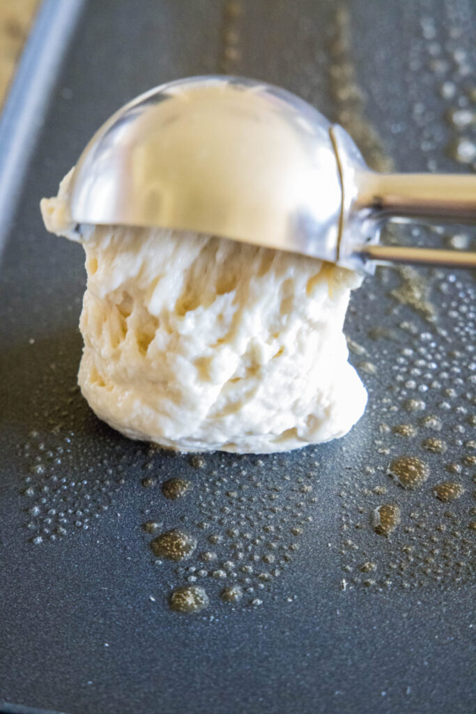 Pancake batter being scooped onto a griddle