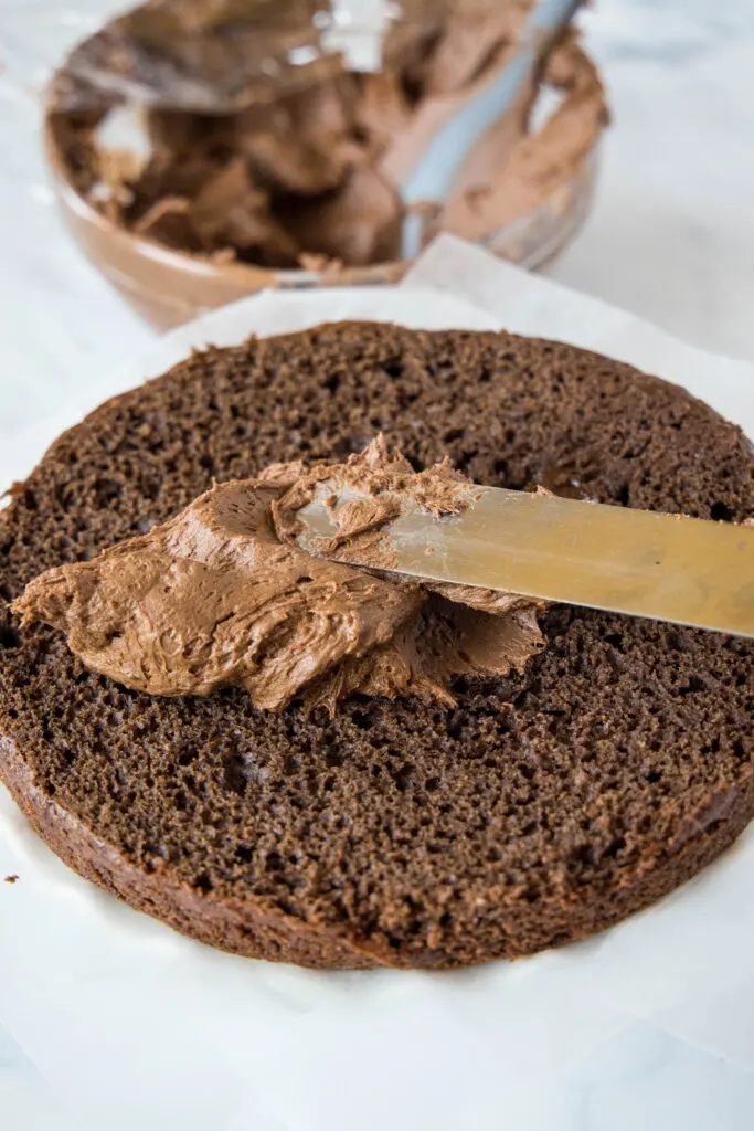 spreading chocolate frosting on a cake
