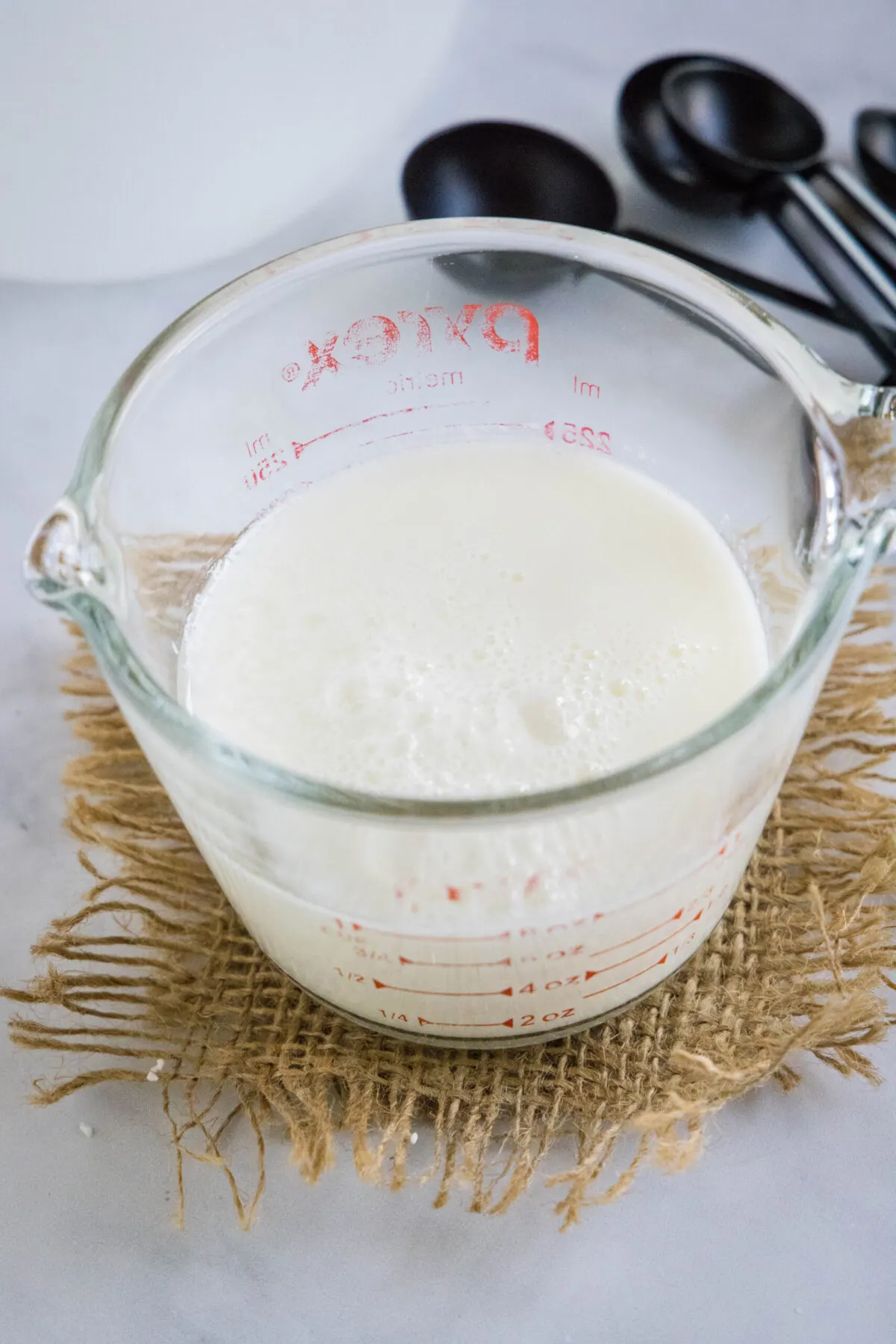 A pyrex of buttermilk with measuring spoons in the background