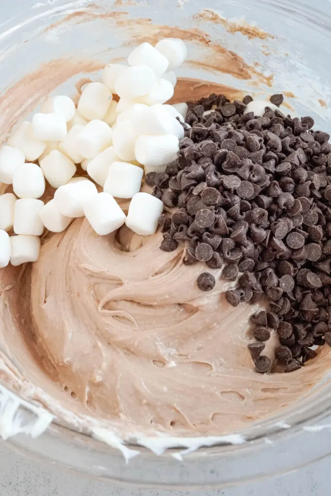 adding marshmallows and chocolate chips to hot chocolate dip