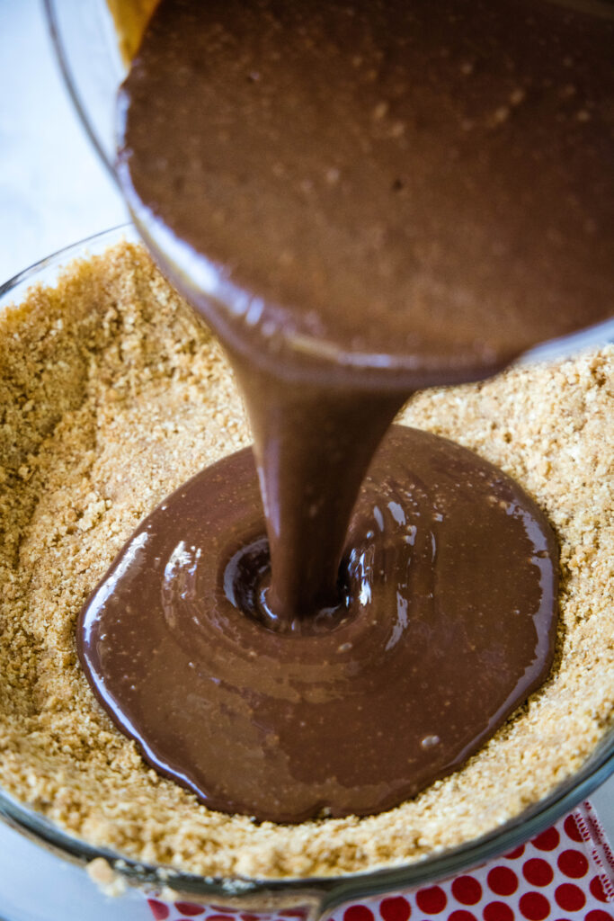 pouring chocolate filling into graham cracker crust