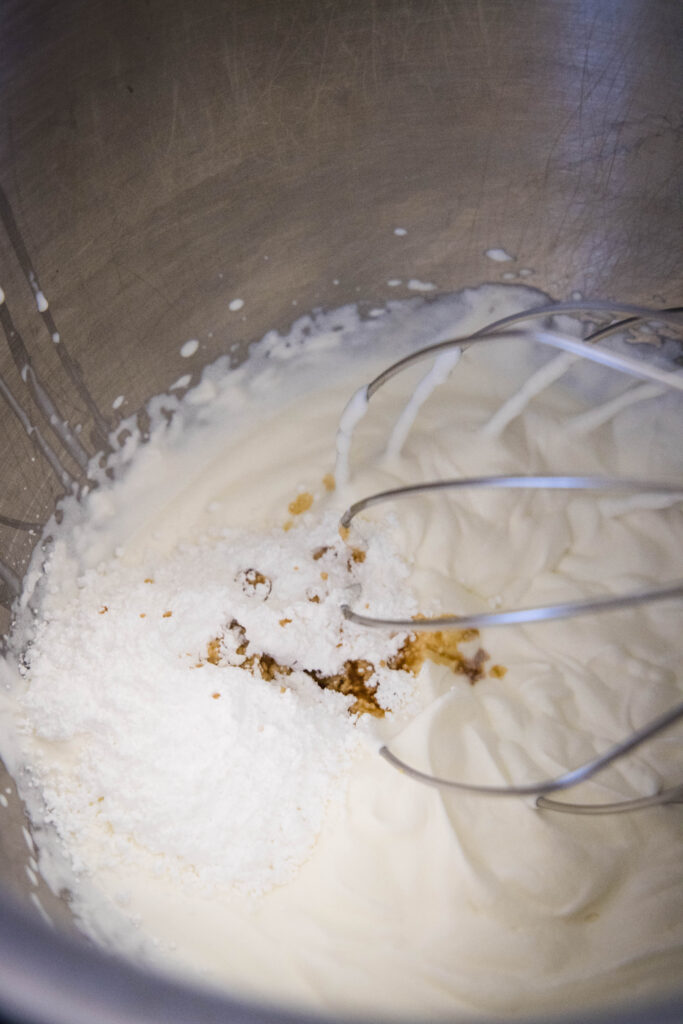adding powdered sugar and vanilla to whipped cream