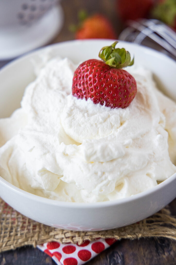 a strawberry sitting in a bowl of whipped cream