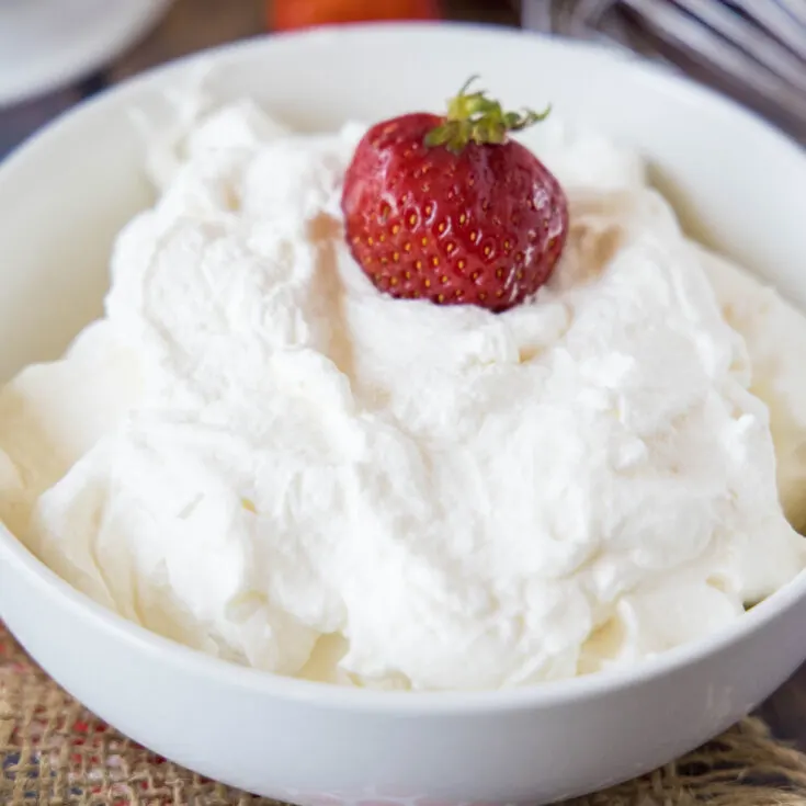 close up bowl of whipped cream with a strawberry in it