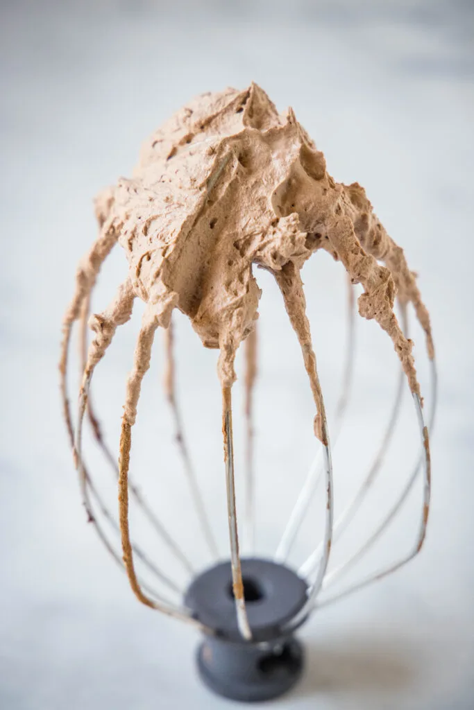 whisk attachment with chocolate whipped cream on it