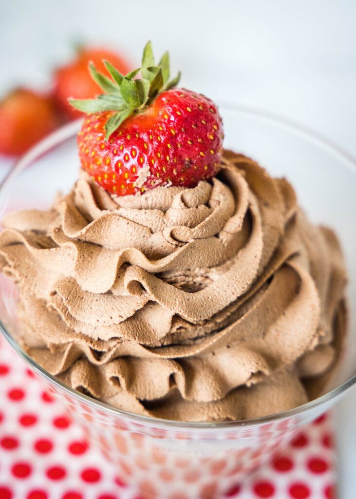 cropped close up chocolate whipped cream topped with a strawberry