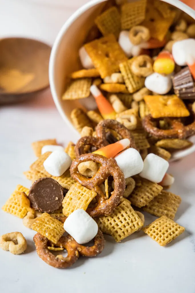 orange bowl on its side with fall snack mix coming out of it