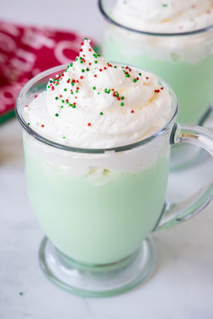 a cup of grinch hot chocolate topped with whipped cream