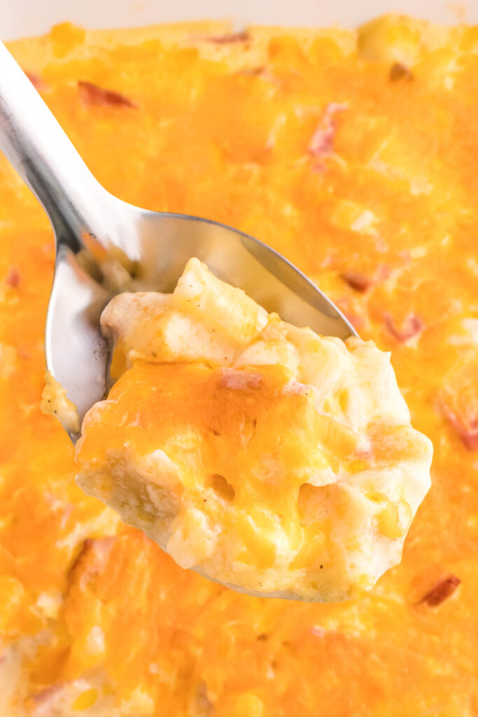 scooping out ham and potato casserole from baking dish