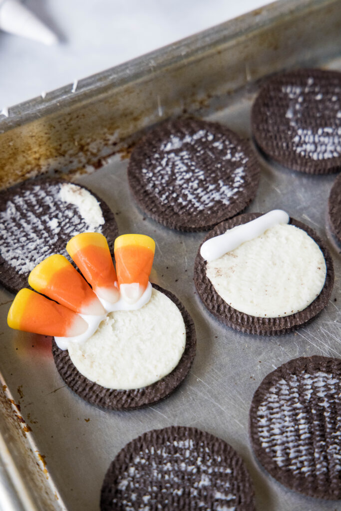placing candy corn into the cream filling of an oreo cookie