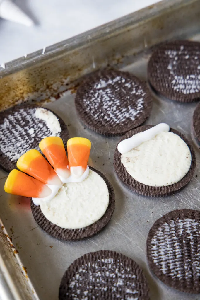 placing candy corn into the cream filling of an oreo cookie