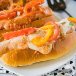 A plate with two sandwiches stuffed with sausage and peppers