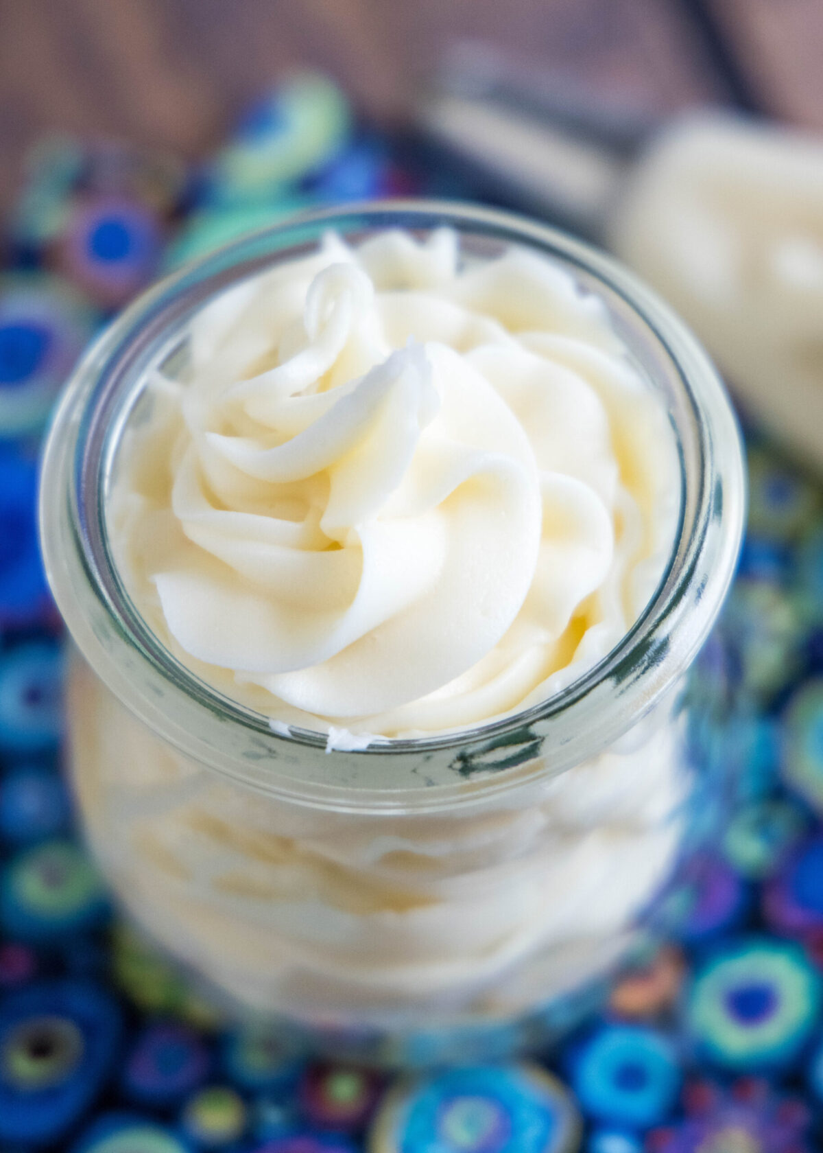 Close-up overhead view of a jar of vanilla frosting next to a piping back