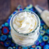 Overhead view of a jar of vanilla frosting next to a piping bag