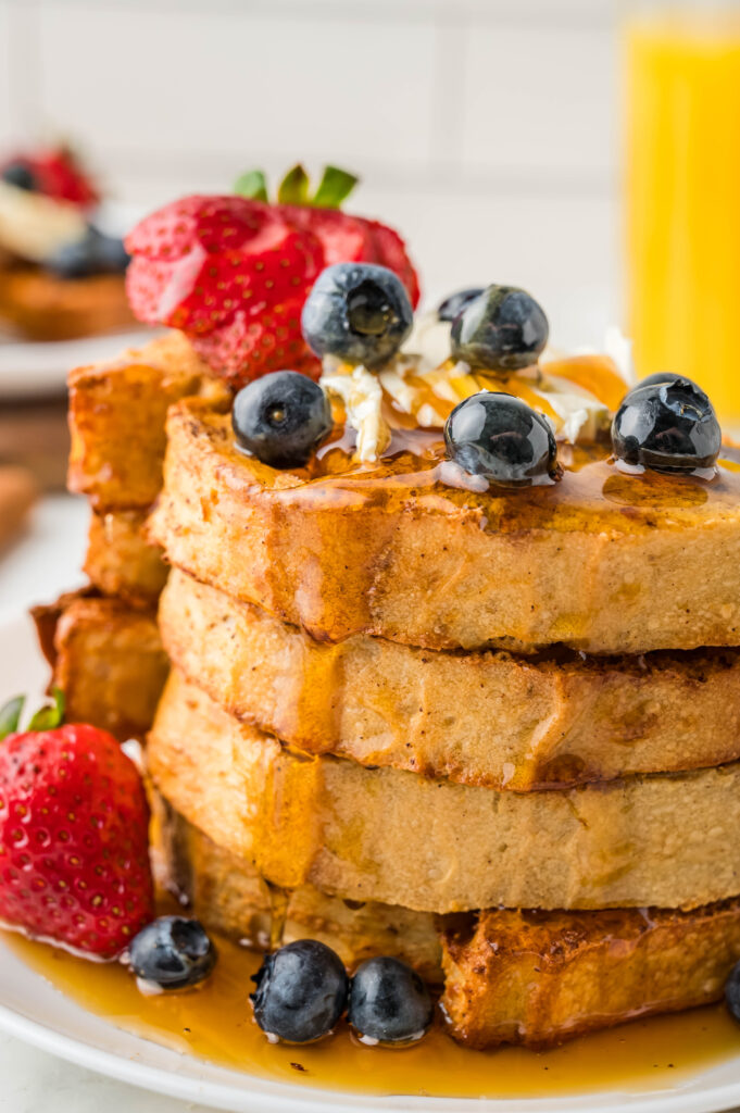 a stack of French toast on a plate with syrup and blueberries