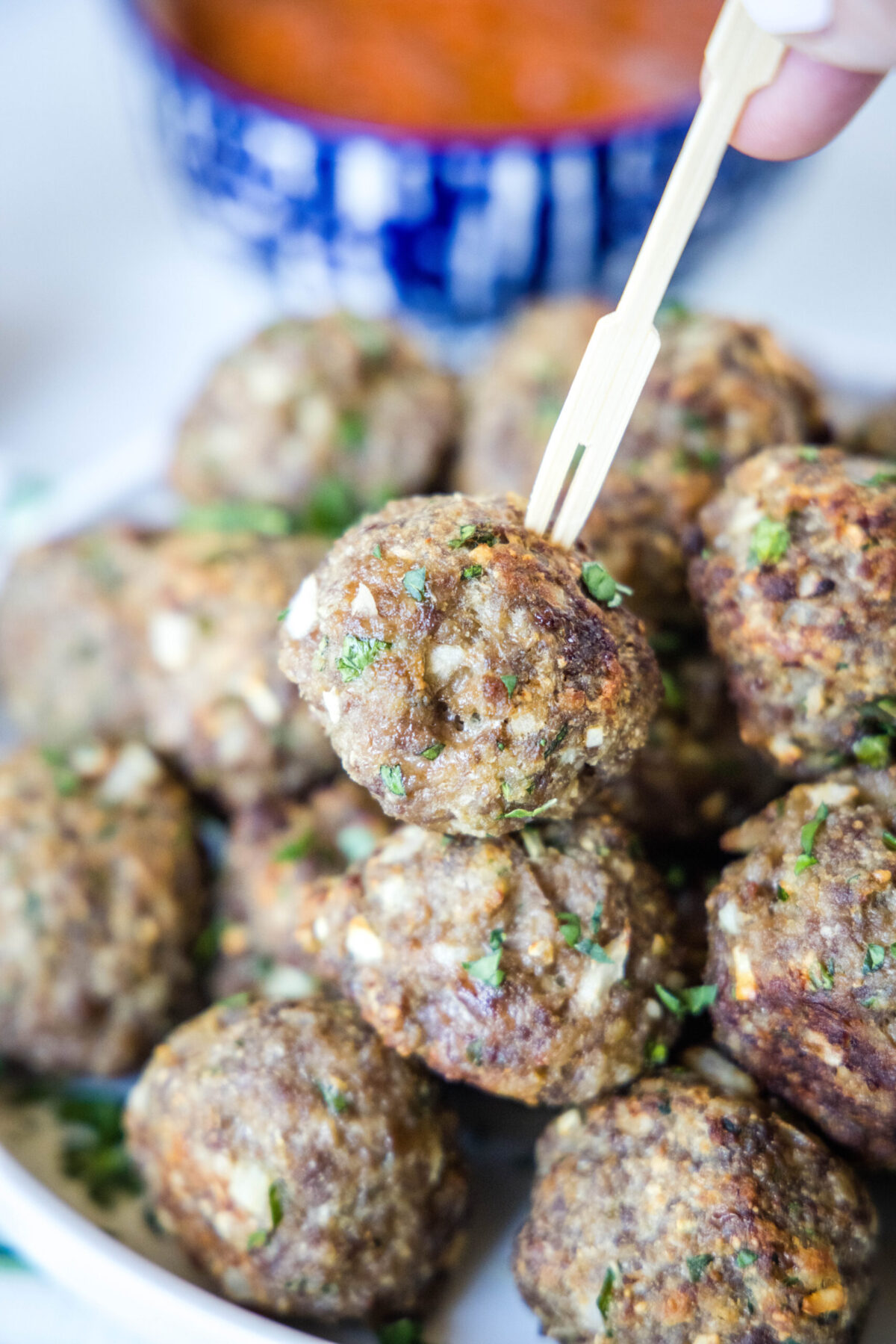 Close up of a plate of meatballs, with one on a skewer