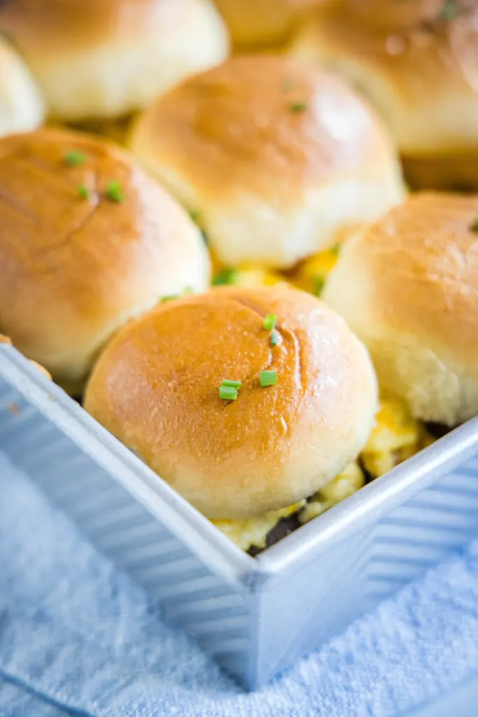 Close up of breakfast sliders in a baking tray, topped with chives