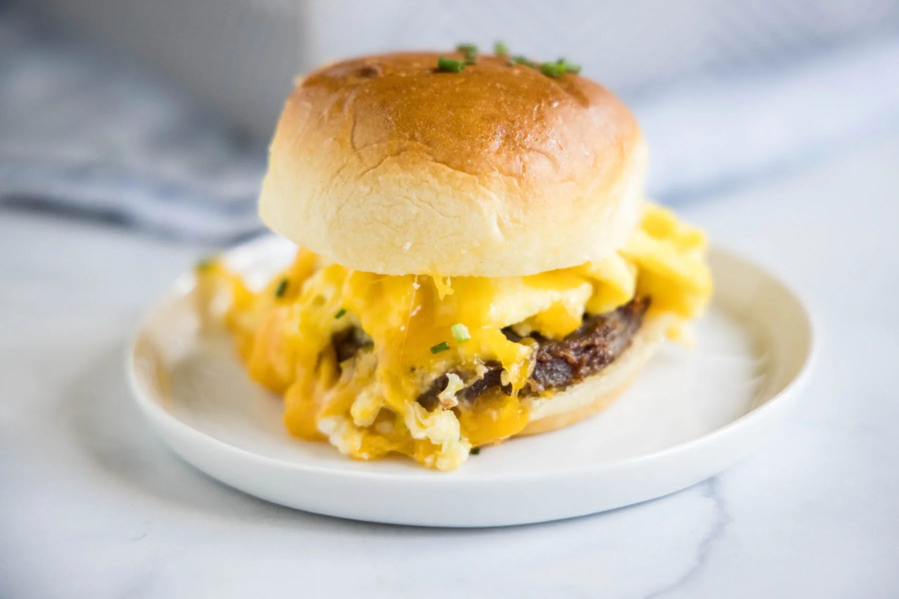 A plate with a breakfast slider full of melty cheese