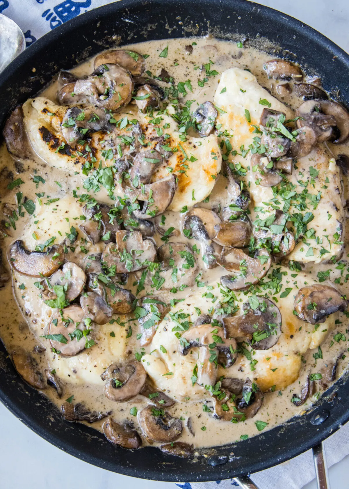 Overhead view of a skillet filled with chicken breasts, mushrooms, and a cream sauce