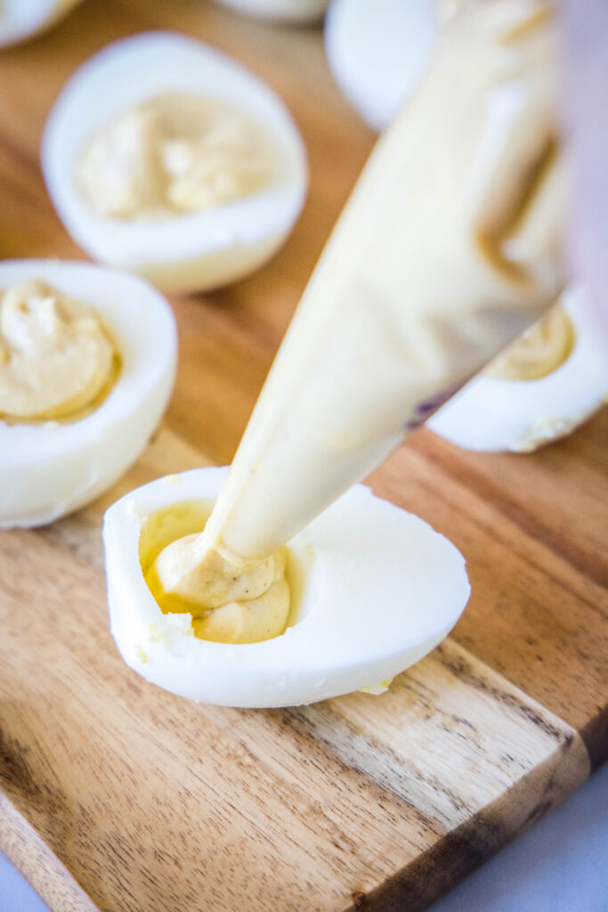 piping deviled egg mixture into eggs