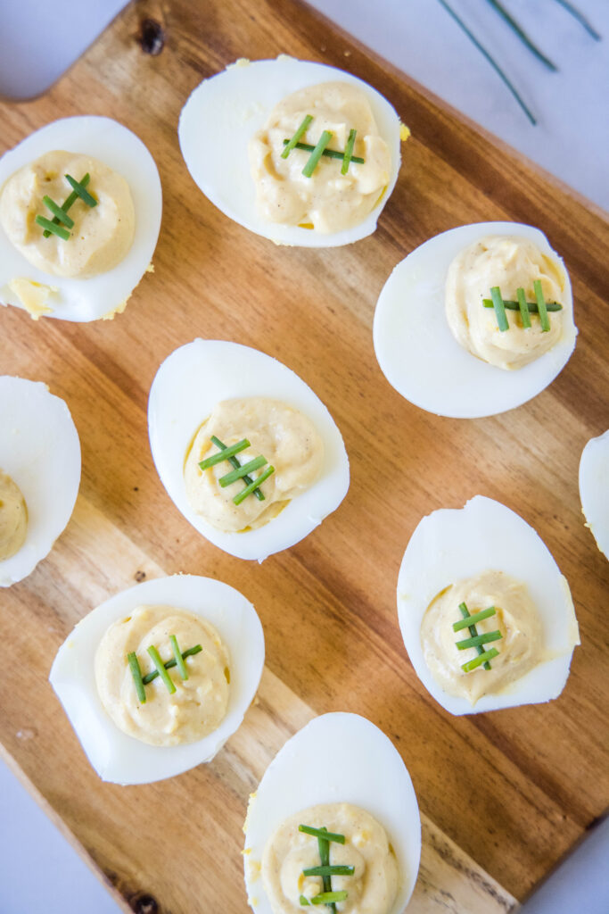 a cutting board with football deviled eggs