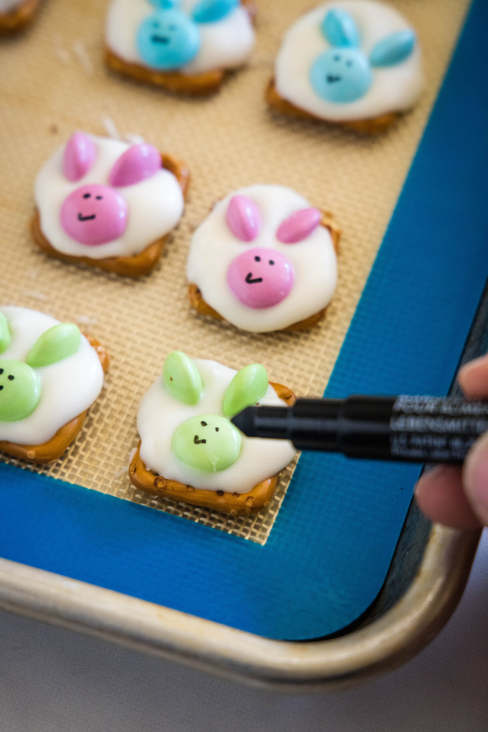 using the marker to draw faces on the pretzel bunnies