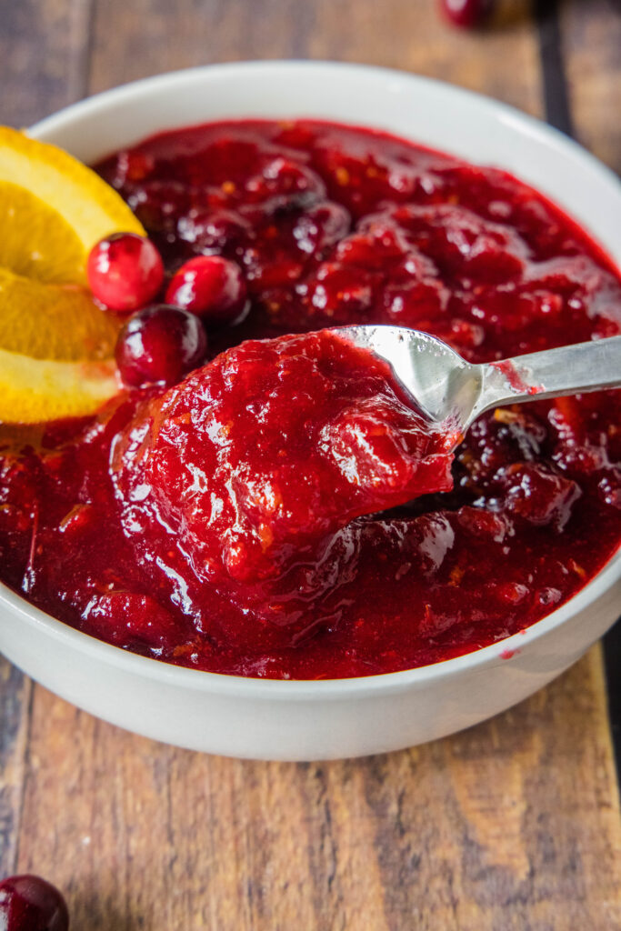 spooning homemade cranberry sauce out of a bowl