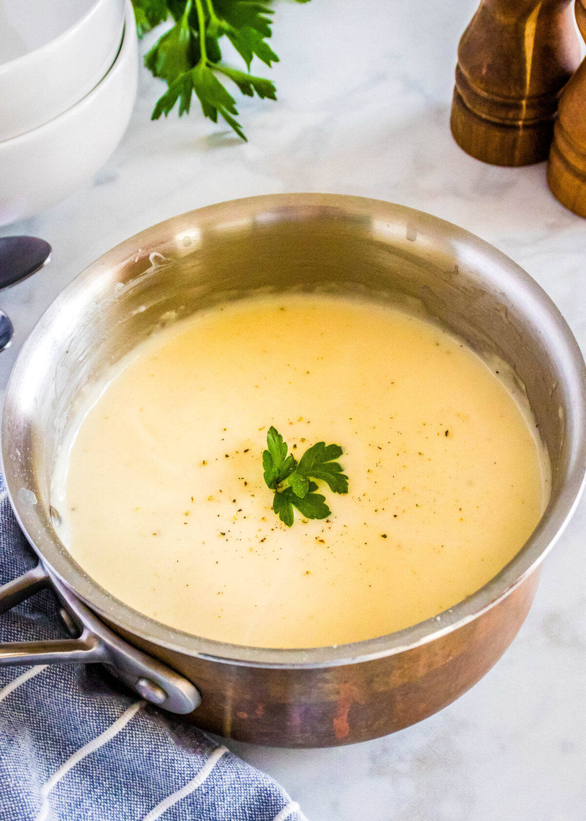 A saucepan filled with cream of chicken soup topped with parsley and pepper.