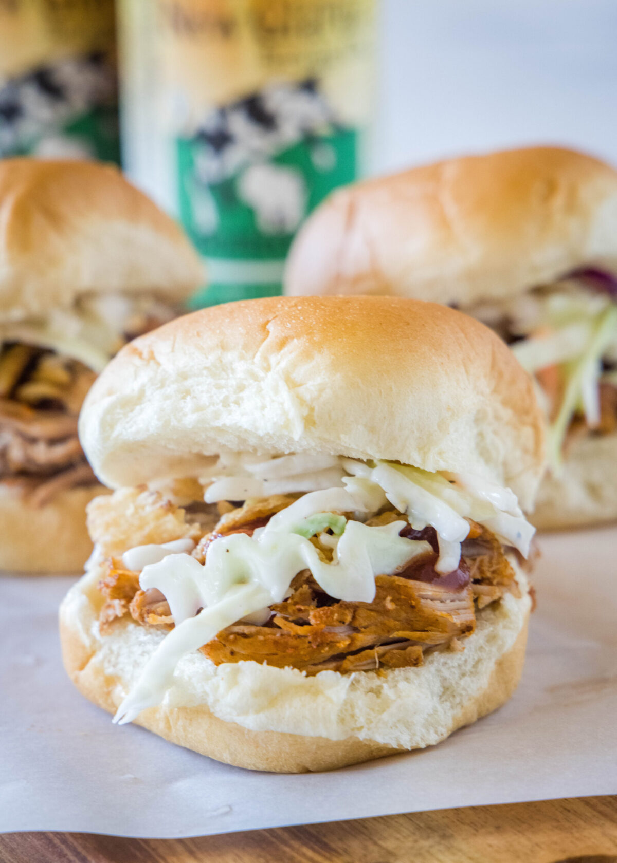 Close up of a pulled pork slider with coleslaw, with two more behind it.