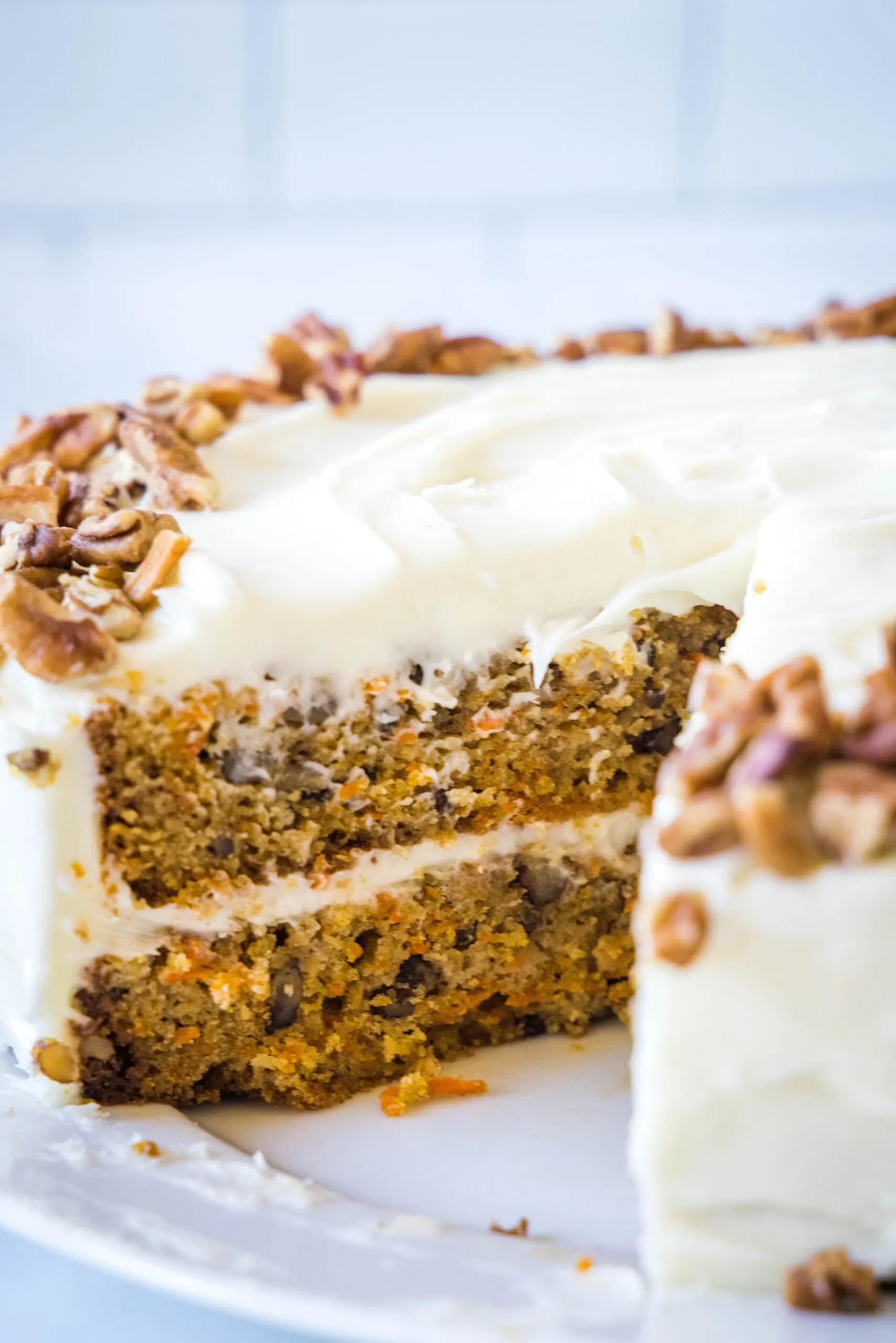 Frosted carrot cake with a slice missing.