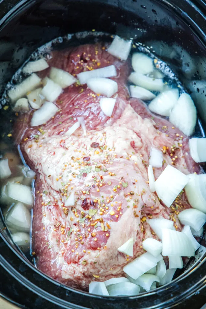Chopped onions added over top of corned beef brisket in the slow cooker.