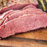 Sliced corned beef on a wooden cutting board.