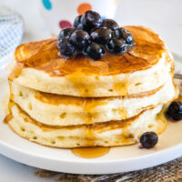 cropped close up of stack of pancakes with syrup and blueberries