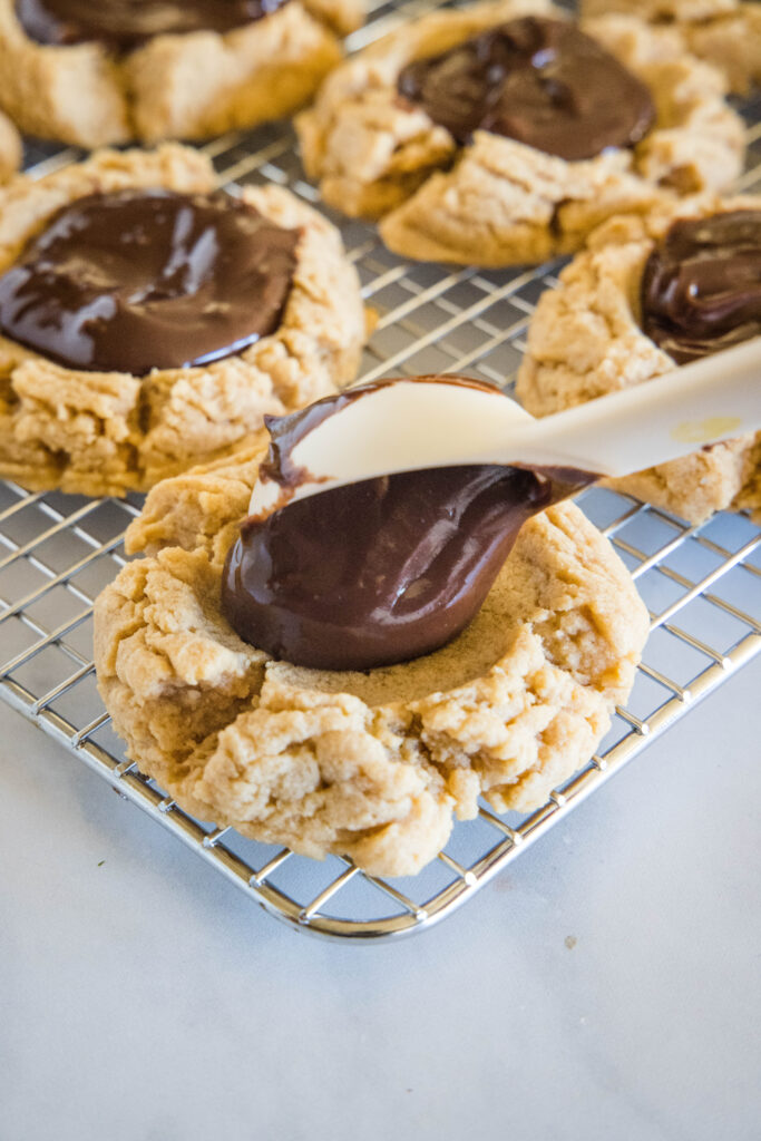 spooning ganache into peanut butter cookies
