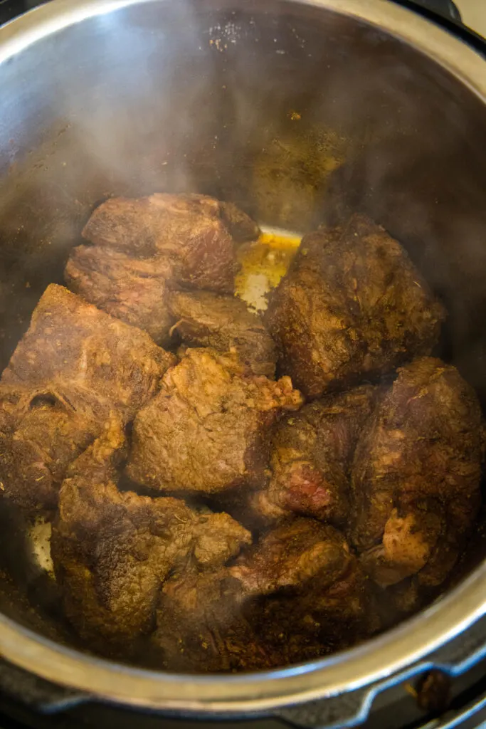 Beef chuck roast pieces browning inside the instant pot.