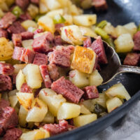 Close up of corned beef hash in a skillet with a serving spoon.