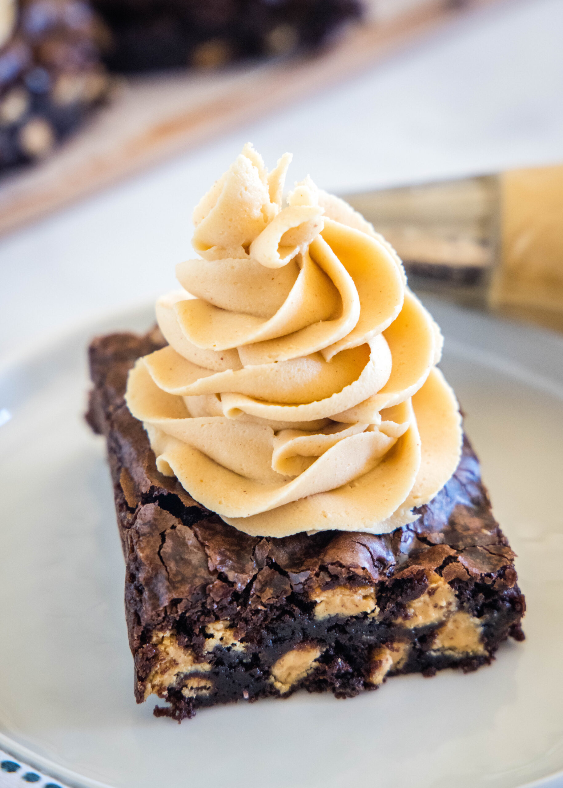 A chocolate brownie topped with a swirl of peanut butter frosting on a plate.