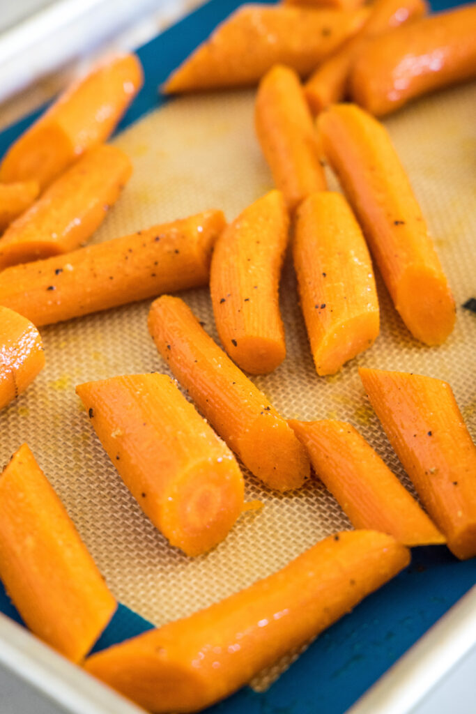 Seasoned carrots on a baking sheet.
