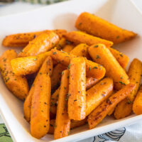 Seasoned roasted carrots in a square white bowl.