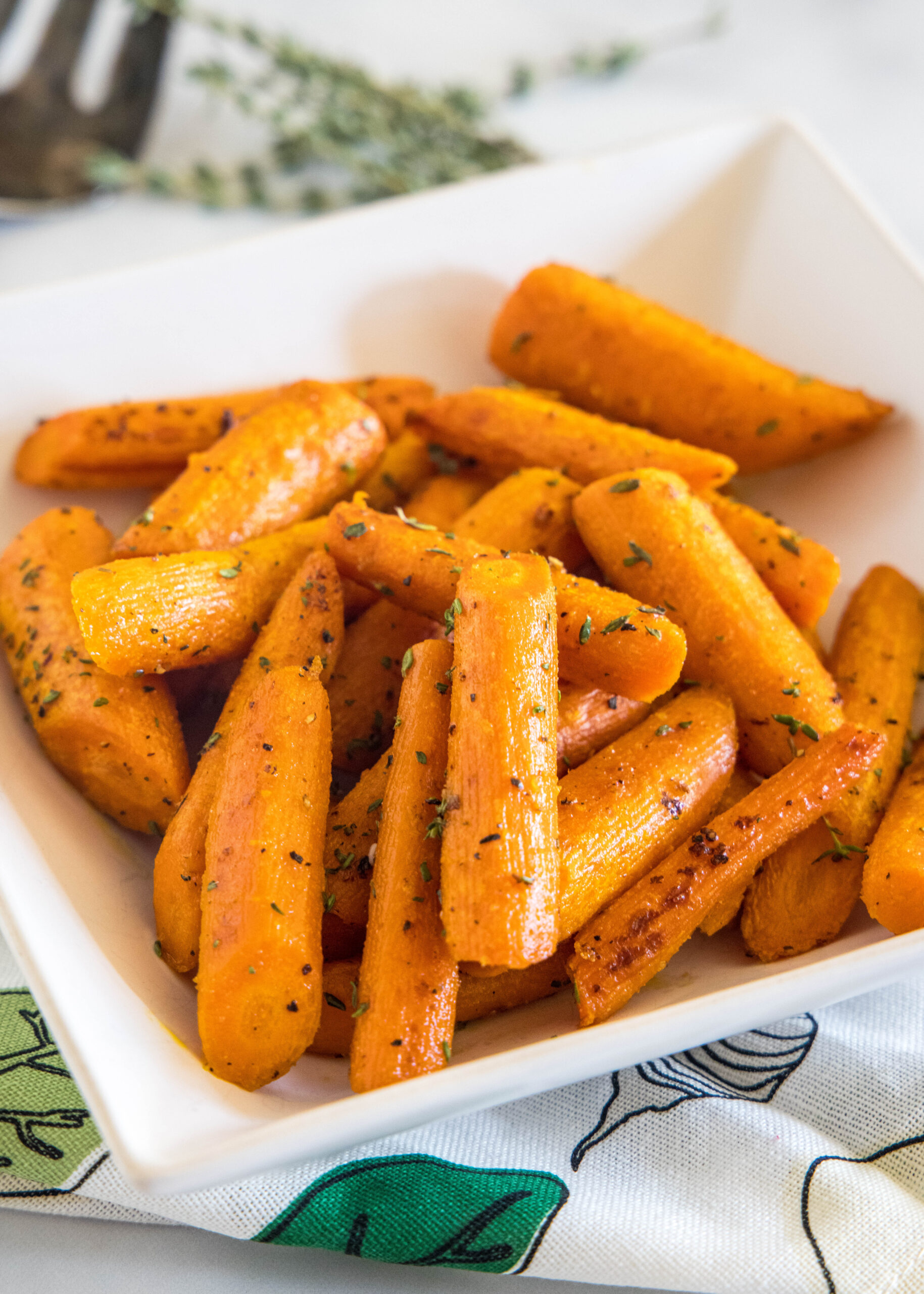 Seasoned roasted carrots in a square white bowl.