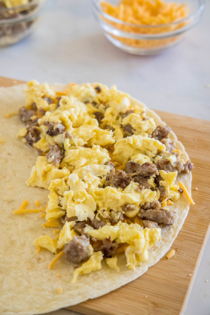 Eggs, sausage, and cheese on one half of a flour tortilla.