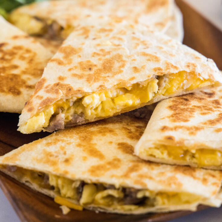Breakfast quesadillas stacked on a wooden serving platter.