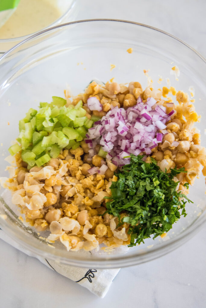 Chickpea chicken salad ingredients combined in a glass bowl.