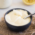 Homemade mayo in a black bowl with a spoon.