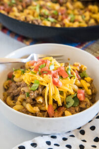 A bowl of taco mac and cheese with a skillet in the background.