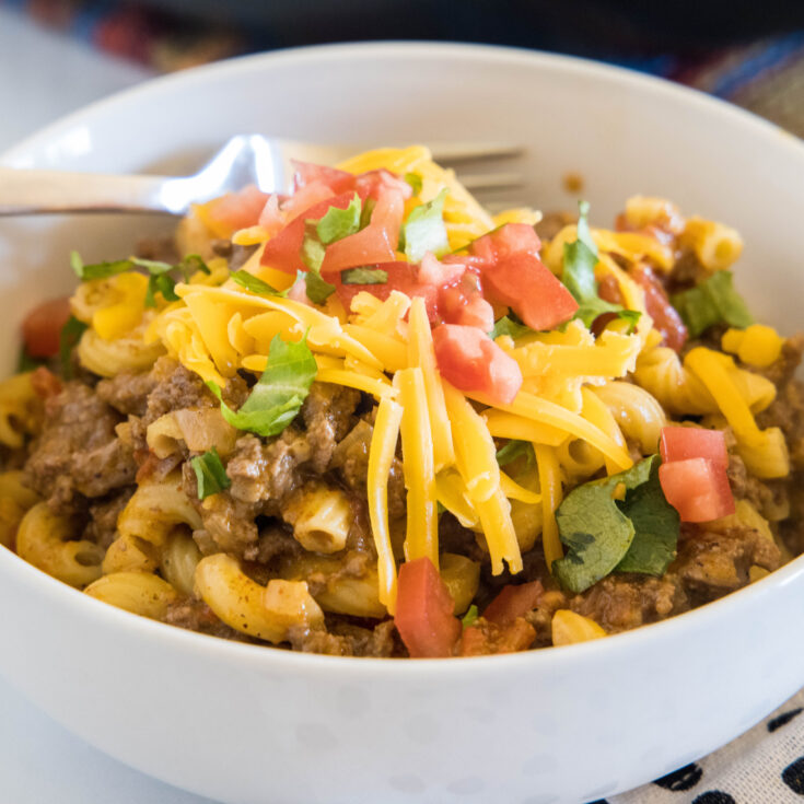 A bowl of taco mac and cheese with a fork.
