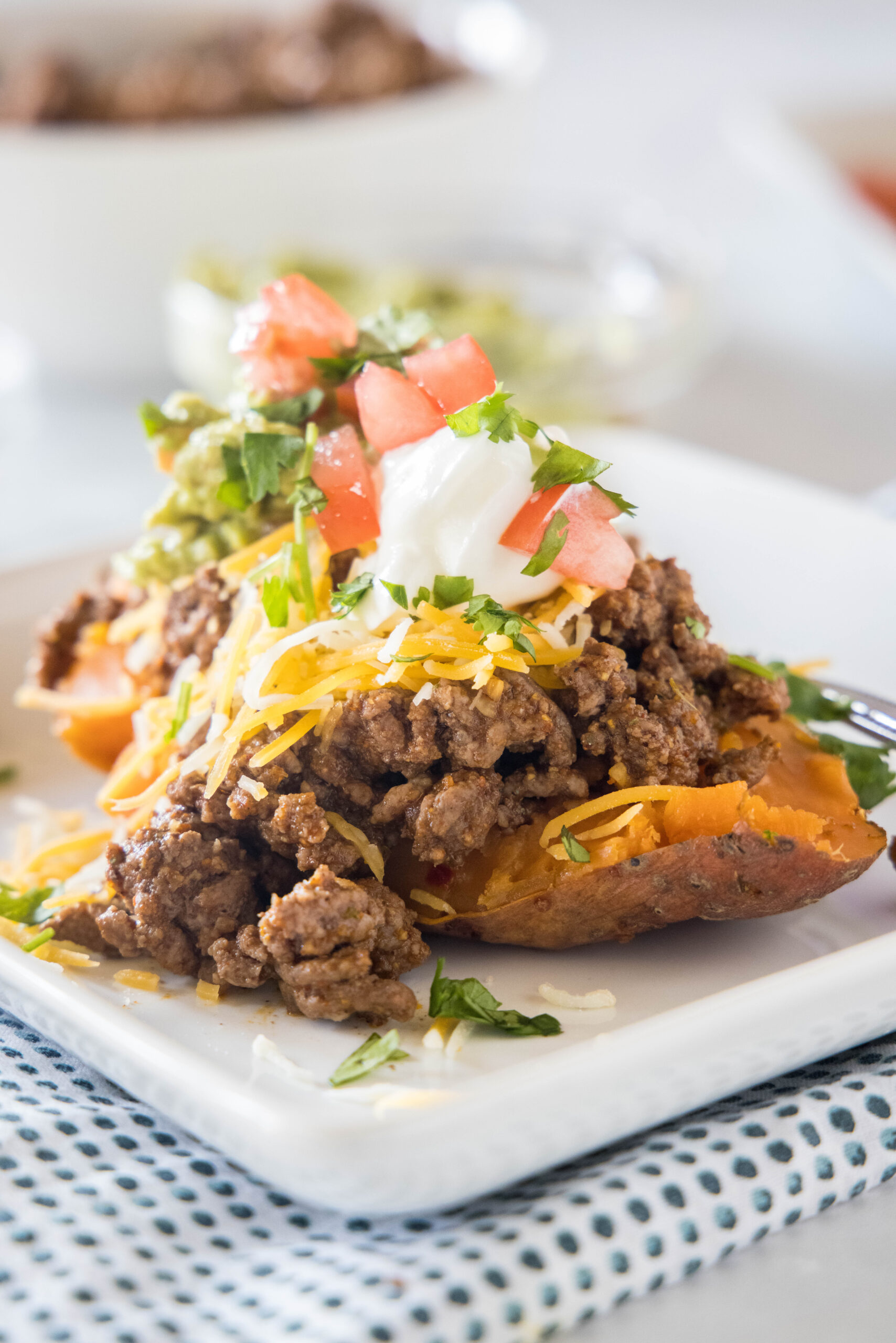 A taco sweet potato piled with taco toppings served on a white plate.