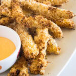 Chicken fries on an oval platter next to a bowl of dipping sauce.